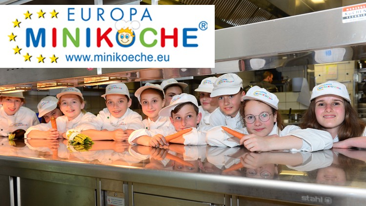 Mehrere Kinder in weißen Kochjacken und Europa Miniköche-Mützen stehen hinter einer Edelstahlküchentheke, Minikoeche-Logo oben.