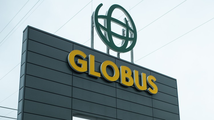 Eingangsbereich eines GLOBUS-Marktes mit gelbem Logo, Luftballon-Dekoration und Schriftzug „Herzlich willkommen“.