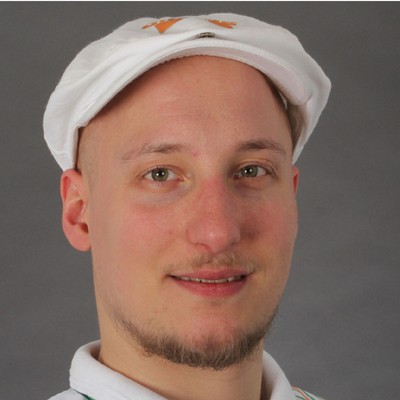 Weiße Mütze mit orangefarbenem Logo und weißes Oberteil mit grün-orangem Streifenmuster vor grauem Hintergrund.