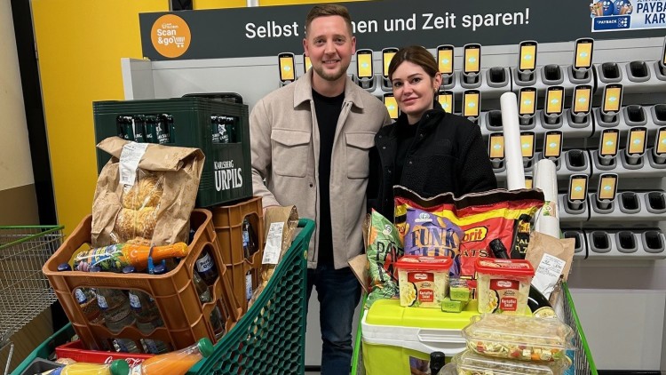 Zwei Einkaufswagen mit Getränkekisten, Lebensmitteln und einer Kühlbox vor einer Scan & Go-Station bei GLOBUS.
