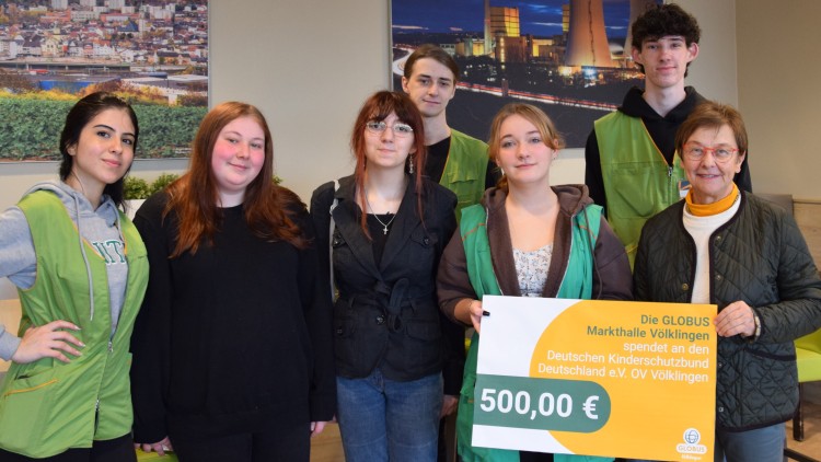 Gruppe mit grüner Kleidung hält ein Schild mit der Aufschrift „Die GLOBUS Markthalle Völklingen spendet an den Deutschen Kinderschutzbund“.