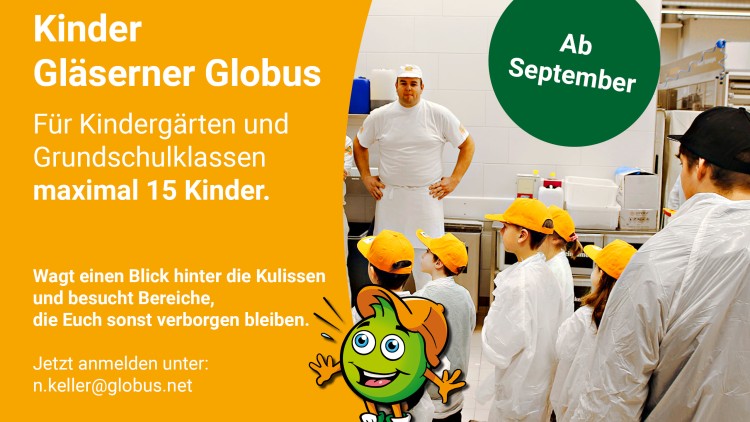 Kinder mit gelben Kappen und weißen Schutzkitteln stehen in einer Küche vor einem Mann in weißer Kleidung und einer grünen Kugel „Globini“.