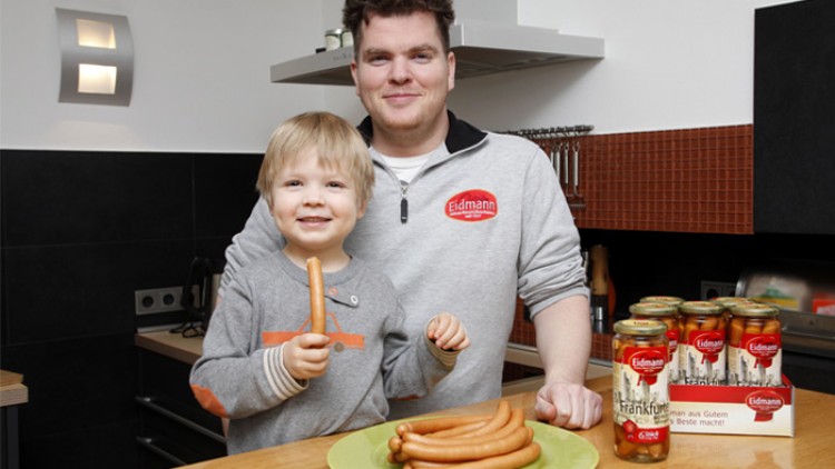 Ein Teller mit Wiener Würstchen steht auf einem Holztisch, daneben sechs Gläser mit der Aufschrift „Eidmann Frankfurt“.