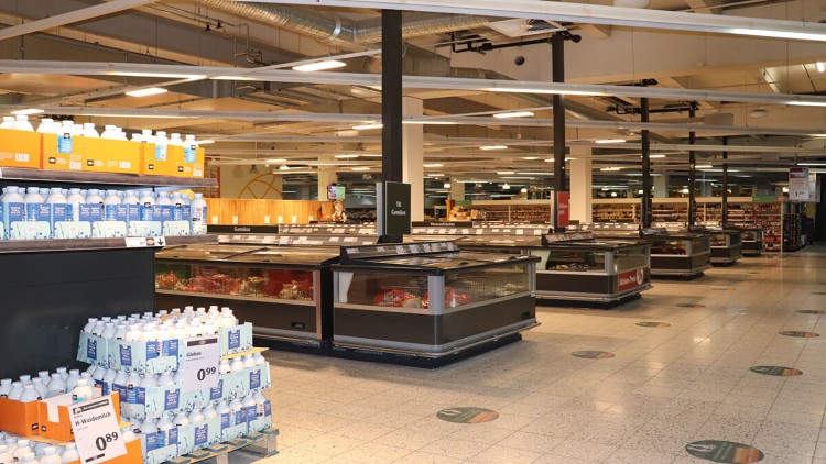 GLOBUS-Markt mit Kühltruhen, Regalen und Paletten mit H-Weidemilch, Schilder für TK-Gemüse und weitere Lebensmittelbereiche.