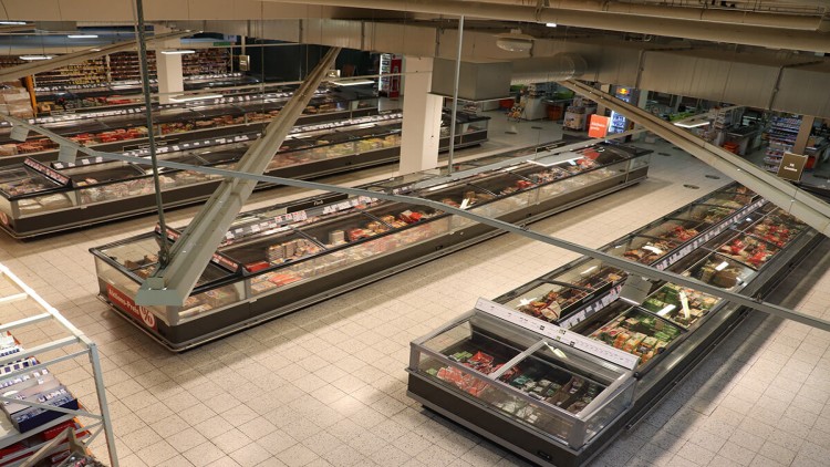 Großer Bereich mit gefüllten Kühltheken in einem GLOBUS Markt, darüber mehrere Metallstreben und sichtbare Lüftungsschächte.