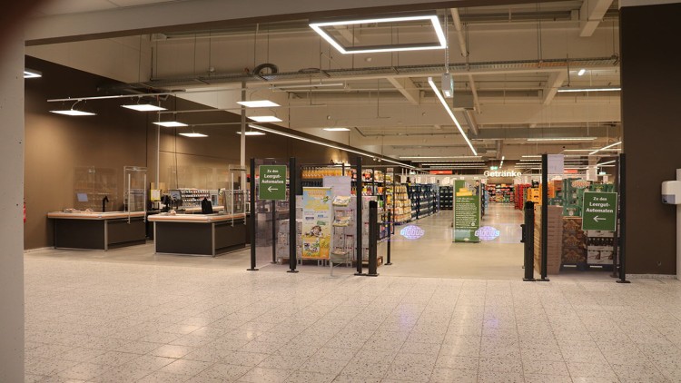 Eingangsbereich in einem GLOBUS-Markt mit Pfandautomaten-Hinweisschildern und Blick in die Getränkeabteilung.