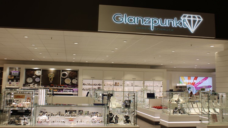 Geschäft für Uhren und Schmuck mit beleuchteter Beschriftung „Glanzpunkt Uhren Schmuck“ und Vitrinen mit Schmuck und Uhren.