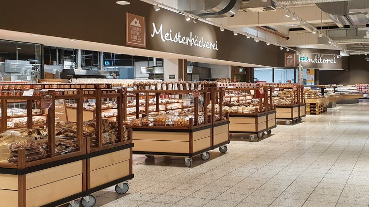 Eine GLOBUS Meisterbäckerei mit Verkaufsregalen voller Brote, Brötchen und Gebäck, Schriftzug „Meisterbäckerei“ an der Wand.