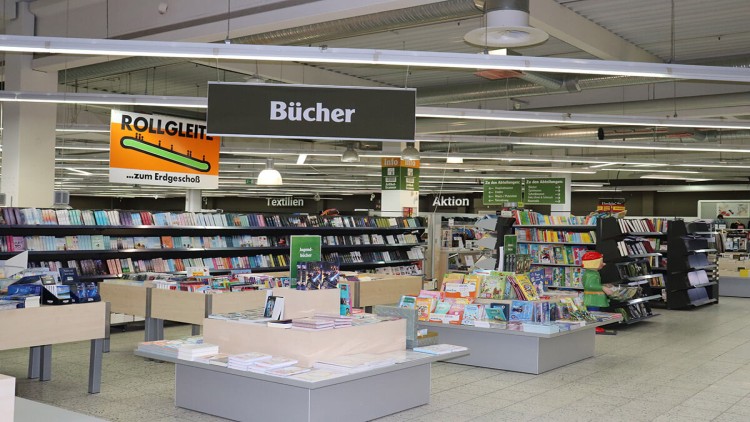 Bücherabteilung im GLOBUS-Markt mit Regalen voller Bücher, einem Globini-Aufsteller und Schildern zu Rollgleit-Anlage und Abteilungen.