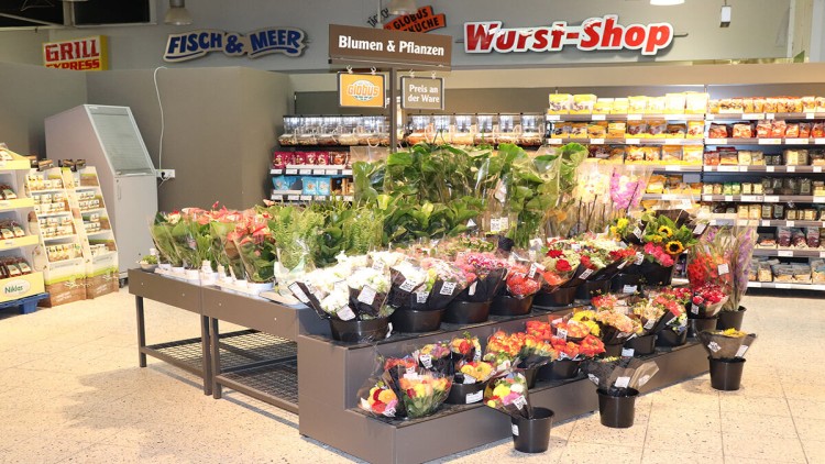 Ein Verkaufsstand mit Topfpflanzen und Blumensträußen ausgestellt unter dem Schriftzug „Blumen & Pflanzen“ im GLOBUS Markt.