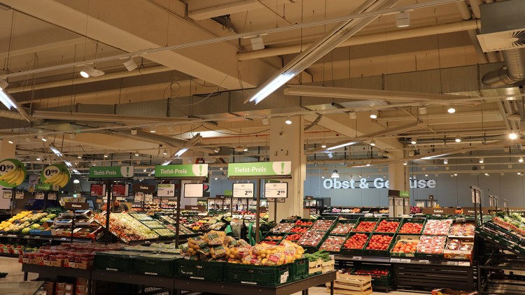 Blick in die Obst- und Gemüseabteilung eines GLOBUS Marktes mit verschiedenen Waren und grünen Schildern mit dem Text „Tiefst-Preis“.