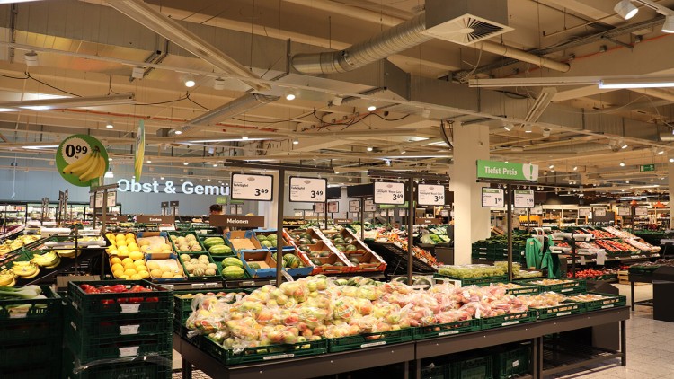 Markthalle von GLOBUS mit Obst- und Gemüseständen, Preisschildern, Leuchtschrift „Obst & Gemüse“ und Deckenbeleuchtung.