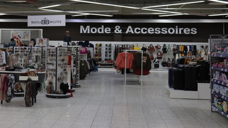 Verkaufsbereich mit Schildern „Bijou Brigitte“ und „Mode & Accessoires“, darunter Schmuck, Taschen, Kleidung und Koffer.