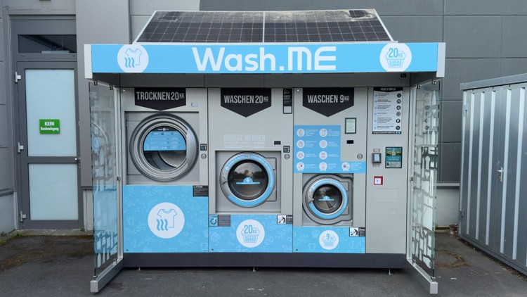 Wäschestation mit drei Maschinen für Trocknen und Waschen, blauer Schriftzug \
