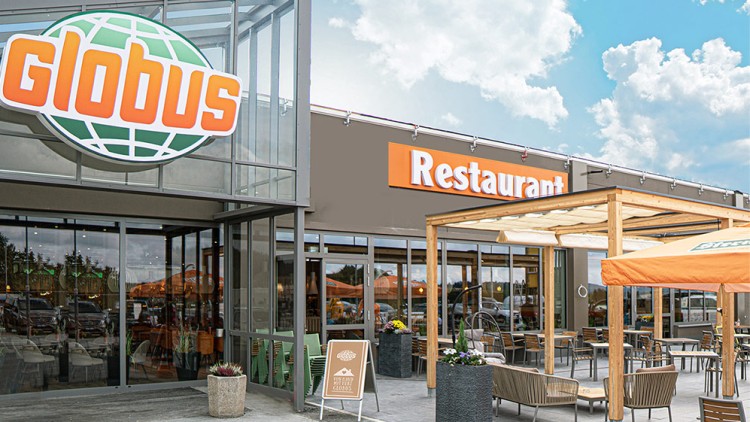 Der Eingang zu einem GLOBUS mit großem Firmenlogo, einem Restaurant-Schriftzug, Sitzbereich im Freien und Hinweisschild.