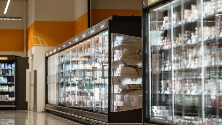 Kühlregale mit Glasschiebetüren und Waren wie Joghurt, Milch und Käse in einem GLOBUS Markt.