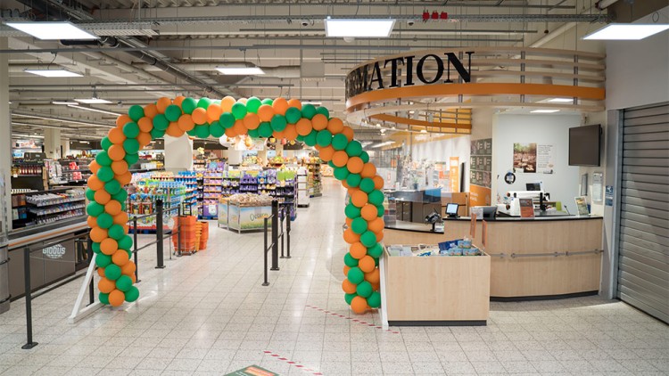 Ein Torbogen aus orange-grünen Ballons vor der GLOBUS-Information mit Blick auf einen Verkaufsbereich.
