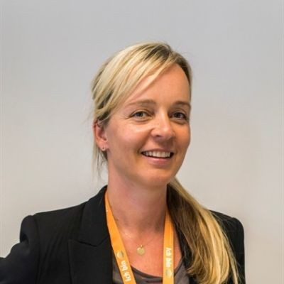 Person mit blondem Pferdeschwanz trägt ein schwarzes Oberteil und einen orangefarbenen Schlüsselband mit GLOBUS-Logos darauf.