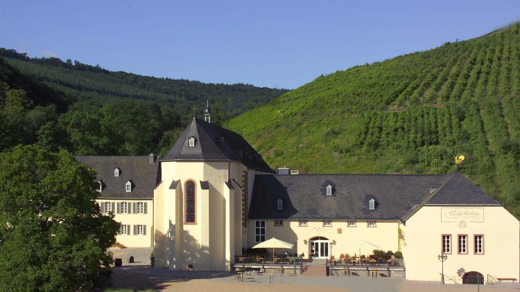 Gelbes Gebäude mit grauem Dach, Kirche mit Spitzfenster, Schriftzug „Kloster Marienthal“, umgeben von Wäldern und Weinbergen.
