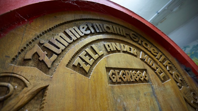 Holzfass mit eingraviertem Text „Zimmermann-Graeff & Müller, Zell an der Mosel, Gegr. 1886“, umrahmt von roter Farbe.
