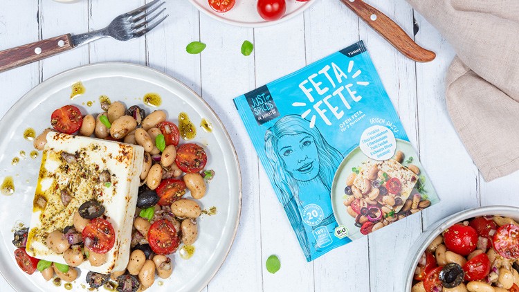 Zwei Teller mit mediterranem Bohnensalat, gebackenem Feta und Oliven, daneben Verpackung mit der Aufschrift Feta Fete.